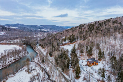  Seasons home in Woodstock VT showing barn-style architecture at sunset Aerial view of private 40-acre estate near Ottauquechee River in Woodstock Vermont