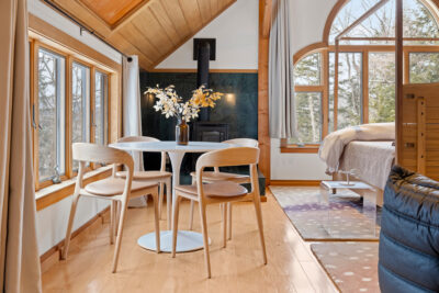 Primary bedroom with cathedral ceiling and large windows facing Vermont woodlands