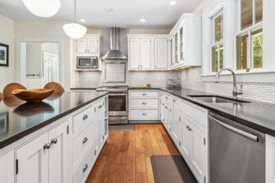 Spacious chef’s kitchen with modern appliances, white cabinetry, and seamless access to a screened porch.