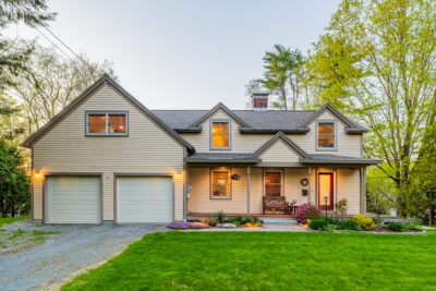 Charming 1949 New Englander home for sale in Hanover NH with white clapboard siding, welcoming front porch, and landscaped front yard