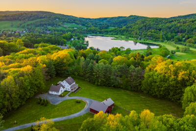 Aerial view of 5-acre property featuring Colonial home, barn, and landscaped grounds in Quechee, Vermont